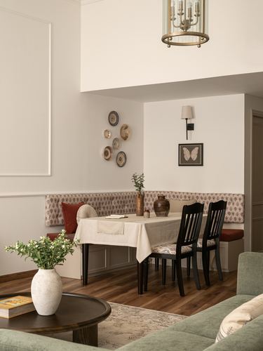 Dining nook with upholstered bench, decorative plates, black chairs, and a brass lantern above a linen-covered table