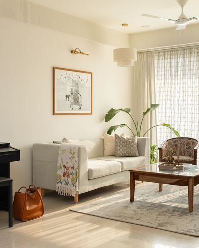 Bright neutral living room with beige sofa, wooden coffee table, patterned armchair and framed art