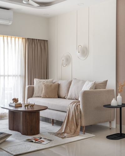 Beige sofa with cushions beside round wood coffee table in minimalist living room