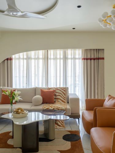 Living room with orange leather chairs, cream sofa, and arched curtained window