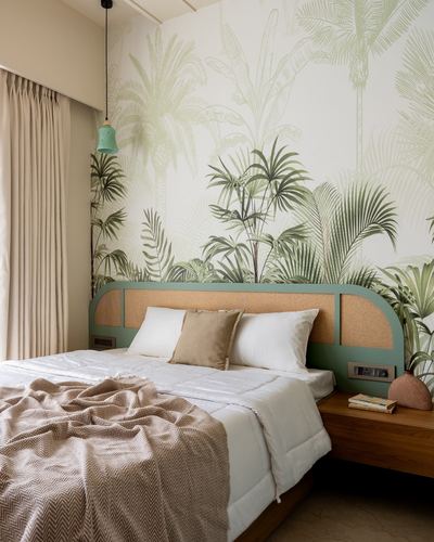 Bedroom with green cane headboard, white bedding, and a tropical leaf mural wall