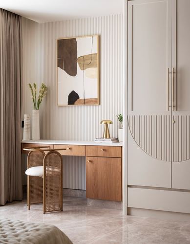 Wooden dressing table with cane stool beneath fluted wall panelling and framed abstract art