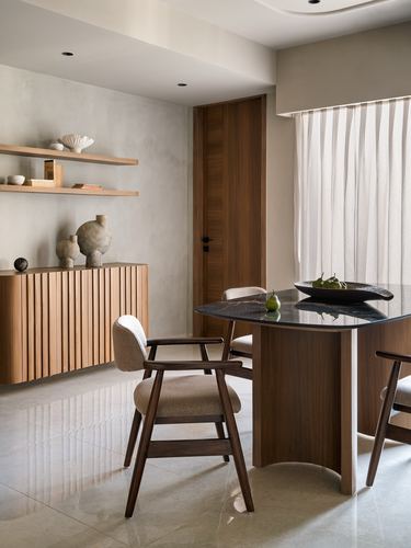 Dining nook with fluted wood cabinet, floating shelves, and dark stone-top table with walnut chairs
