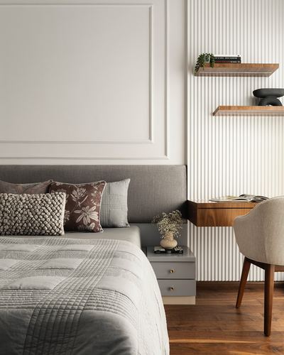 Grey upholstered bed against panelled wall beside fluted wood wall with floating shelves and desk