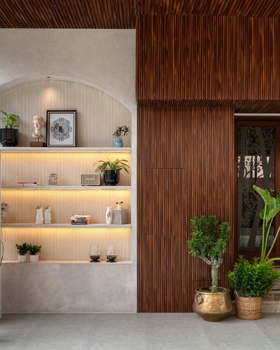 Arched niche shelving with backlit ribbed panels beside a fluted wood wall and potted plants in entryway