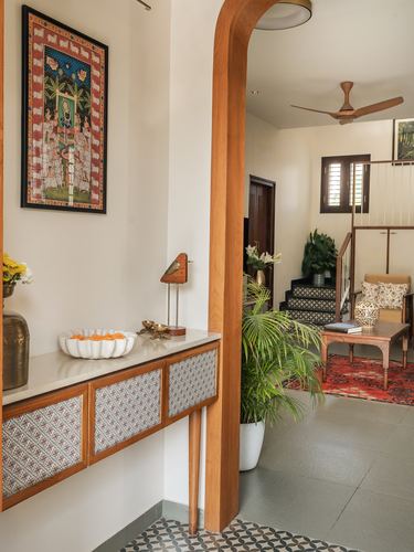 Wooden archway leading from a foyer console to a living room with staircase and seating