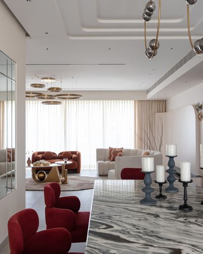 Marble kitchen island with candle holders overlooks a living room with rust sofas and brass pendant lights