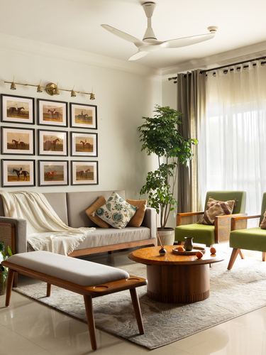 Living room with cane armchairs, round wooden coffee table, and gallery wall of horse prints