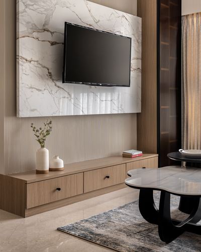 Wall-mounted TV on marble panel above a wood veneer console with vases and books