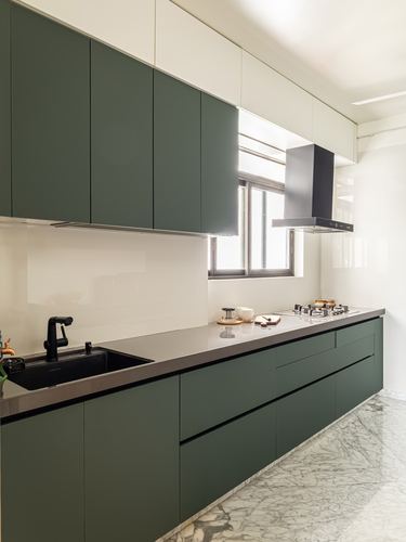 Modern galley kitchen with dark green base cabinets, white upper units, black hood and marble floor