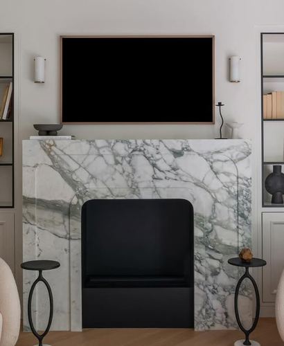 Green-veined marble fireplace with mounted tv above, flanked by built-in shelving and slender black side tables.
