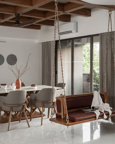 Dining area with wood coffered ceiling and a chain-hung wooden swing bench with maroon cushions