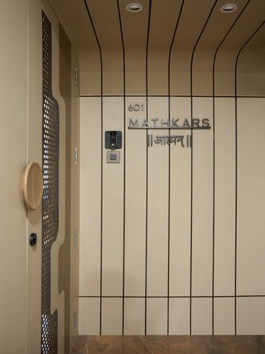 Entrance door with perforated metal jaali panel beside a fluted wall bearing '601 Mathkars' nameplate