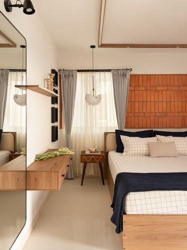 Bedroom with terracotta tile headboard, navy and white bedding, wooden console and mirror