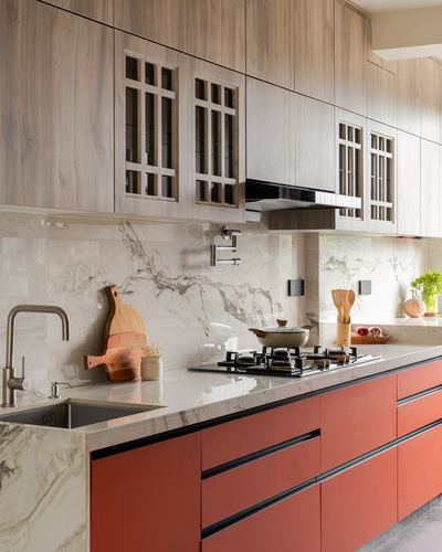 Modern kitchen with terracotta cabinets, marble backsplash, wood-toned upper cabinetry and gas hob