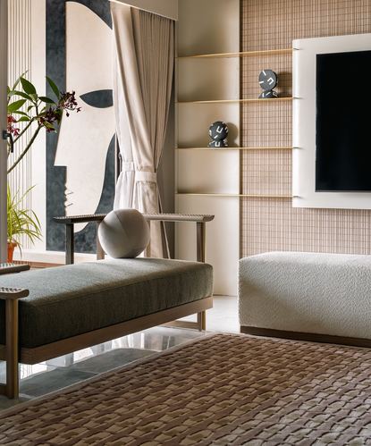 Living room corner with wooden bench, boucle ottoman, textured wall shelving and abstract art panel