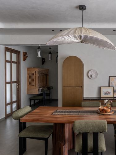 Dining room with live-edge wood table, olive chairs, and sculptural woven pendant light