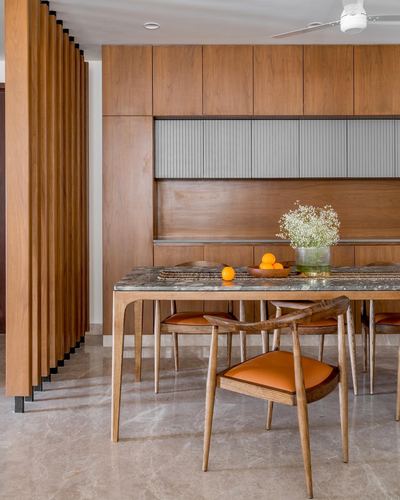 Wooden dining room with marble-look table, orange leather chairs, and fluted wood screen