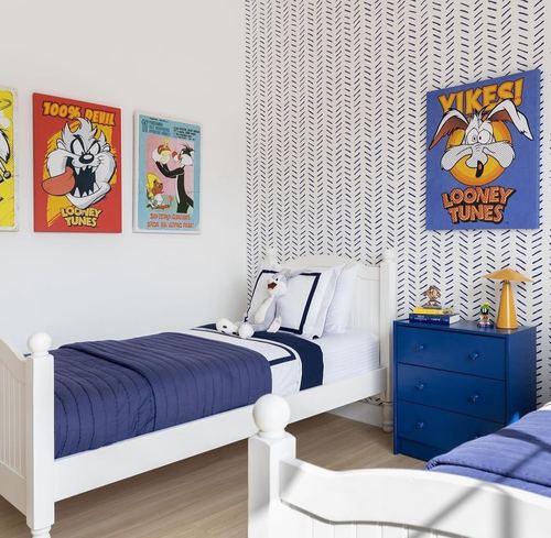 Kids bedroom with twin white beds, navy bedding, patterned wallpaper and Looney Tunes posters