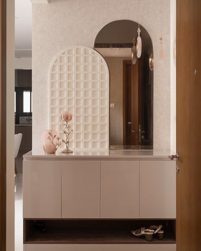 Entryway console with arched mirror, textured white lattice niche, and pink decor accents