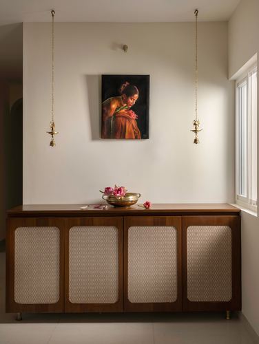 Sideboard with cane panels beneath a portrait painting flanked by hanging brass lamps