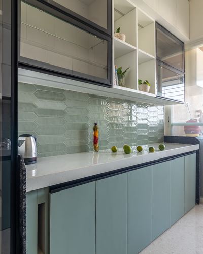 Galley kitchen with sage green cabinets, glossy hexagonal tile backsplash, and glass-front upper units