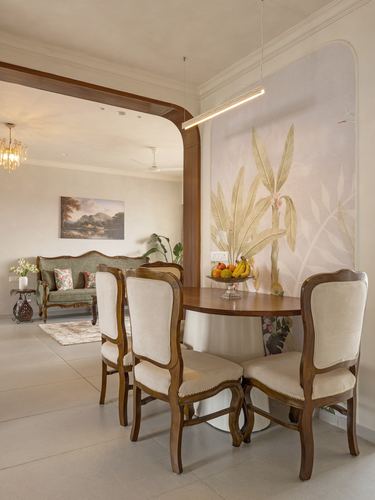Dining table with cream upholstered chairs beneath a linear pendant and botanical mural wall
