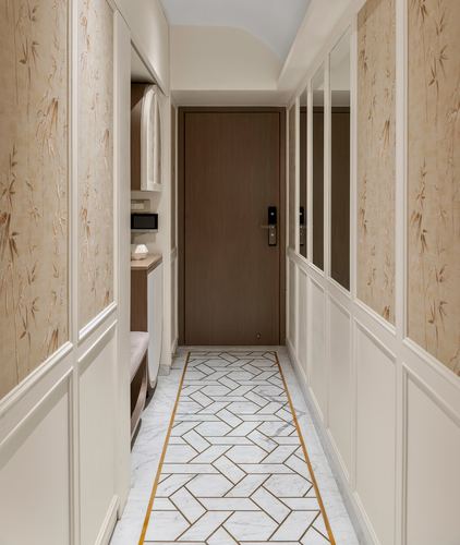 Narrow entry foyer with wood-paneled door, mirrored side panels, and brass-inlaid marble flooring