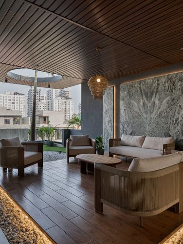 Covered outdoor lounge with wood ceiling, stone wall, and woven furniture overlooking city skyline