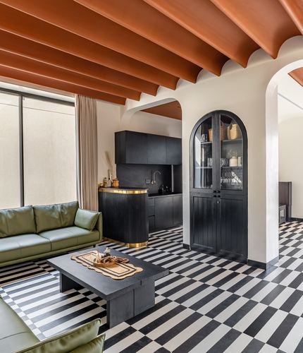 Living room with checkerboard floor, olive sofa, black arched cabinet, terracotta ribbed ceiling