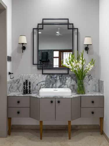 Bathroom vanity with marble counter, vessel sink, geometric black mirror and sconces