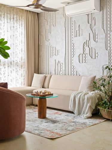 Beige sofa against textured relief wall with wooden pedestal coffee table and chess set