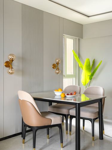 Dining nook with fluted grey paneling, black chairs, marble table and brass sconces