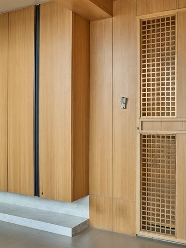 Wood-paneled entryway with lattice screen door and stone step in Ahmedabad apartment