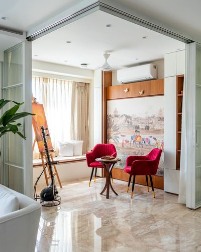 Living nook with red velvet chairs, mural wall, sitar, and marble flooring in Mumbai home
