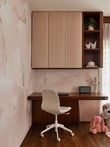 Child's study nook with fluted pink wardrobe, wood shelving, desk, chair, and hot air balloon wallpaper
