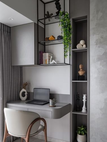 Floating grey desk with laptop beneath open metal shelving and a niche display unit with sculptures