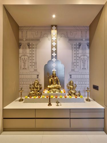 Pooja niche with brass deity idols before an illustrated temple facade mural