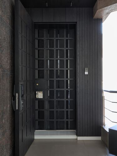 Dark wood-paneled entryway with an open door revealing a lattice screen door behind it