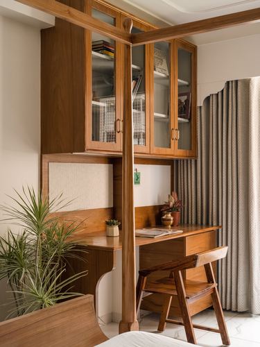 Wooden corner study nook with glass cabinets, desk, chair and curtains beside a bed