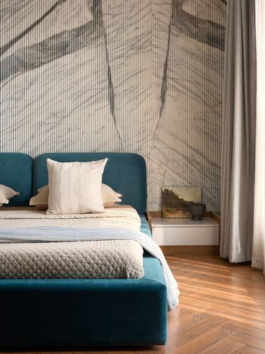 Teal velvet bed against a veined stone wall with wood floors and a floating nightstand