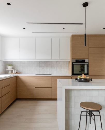 Modern white and wood kitchen with waterfall island, pendant light, and textured tile backsplash
