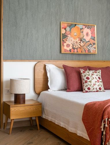 Bedroom corner with curved wood headboard, floral cushions, and framed floral art above