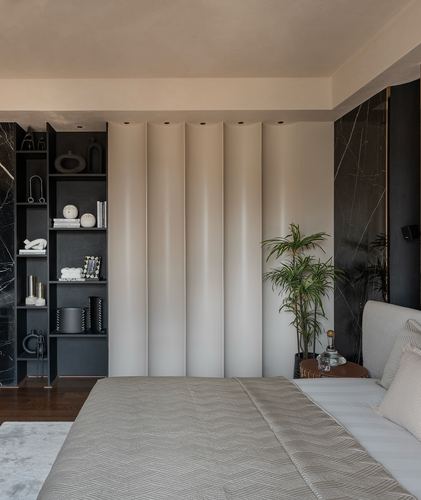 Bedroom with fluted beige headboard wall, dark stone accent, and open shelving with curated objects