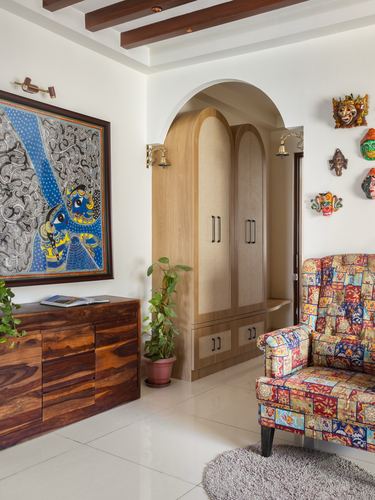Foyer with arched wooden wardrobe, patchwork armchair, folk painting and wall masks