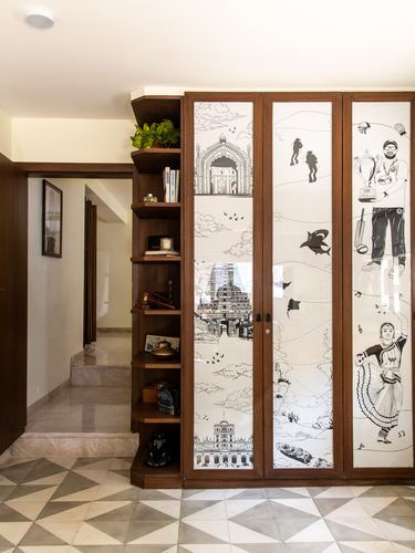 Wooden wardrobe with illustrated glass panels beside open shelving and staircase on geometric tile floor