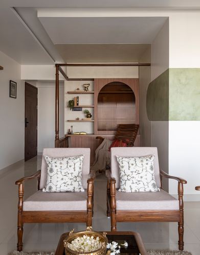 Living room with twin wooden armchairs facing an arched wood cabinet and open shelves