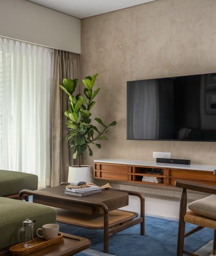 Living room with teak console, cane chair, blue rug, and textured stucco wall behind tv