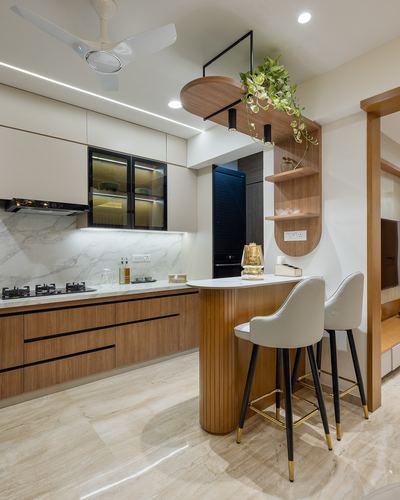 Modern kitchen with wood cabinetry, marble backsplash, and curved breakfast bar with two stools