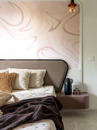Bed with mauve upholstered headboard against curved arched wall with marbled mural and floating nightstand